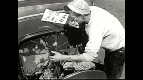 A schoolboy works on his hotrod while reading Hot Rod magazine and, after a test Video stock 86824958