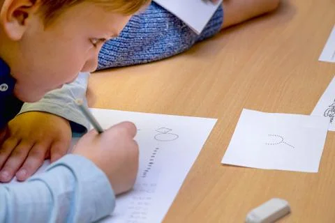 Schoolboy writes on a sheet of paper Stock-Fotos