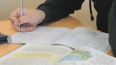 Schoolboy writes text in exercise book on lesson Stockbeeldmateriaal 70179479