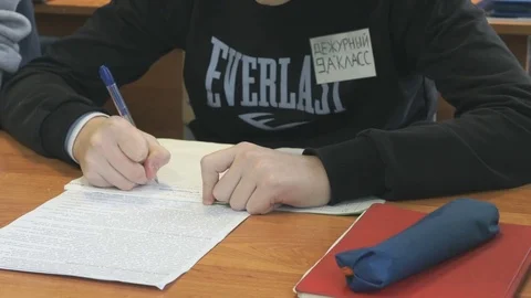Schoolboy writes text in exercise book on lesson Stock Footage 71605461