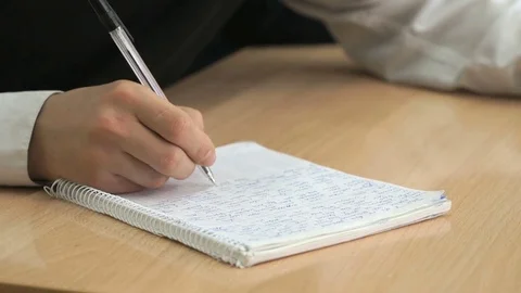 Schoolboy writes text in exercise book using a pen Stock Footage 78648906