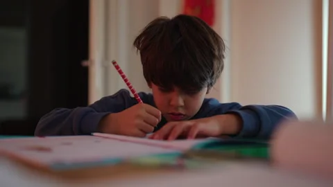 Schoolboy writing in an activity workbook at home study table, building con.. Stock Footage 343662719