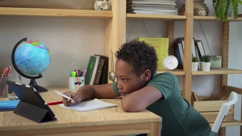 Schoolboy writing and talking, sitting at table with tablet during online study Stock-Footage 165190922