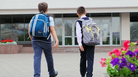 Schoolboys with large backpacks walk to school building Video stock 133484817