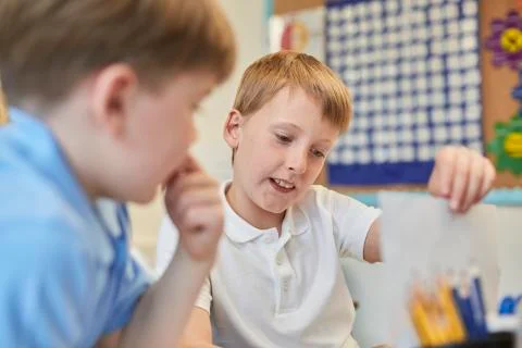 Schoolboys learning together in classroom lesson at primary school Stockfoto's