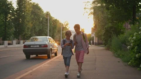 The schoolboys returning from school in a sunset time. Stock Footage 157700274