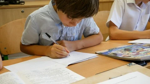 Schoolboys Sitting At The School Desk on the Lesson and  Writes in a Notebook Stock Footage 93889625
