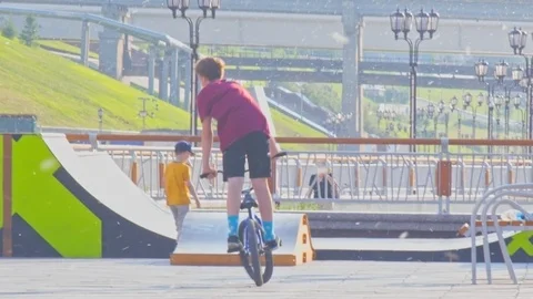 Schoolboys train to ride bikes in city park on summer day Video stock 104171027
