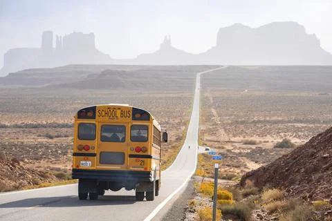 Schoolbus moving on road leading towards Monument Valley during summer Foto stock