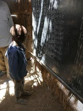 Schoolchild solving arithmetic problems inside weathered classroom, represe.. 写真素材