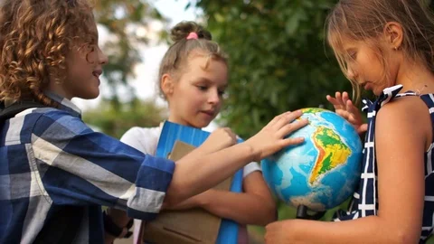 Schoolchildren are considering a large globe. Outdoor portrait. Back to school Stock Footage 114017916