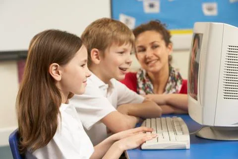 Schoolchildren In IT Class Using Computer with teacher 스톡 사진