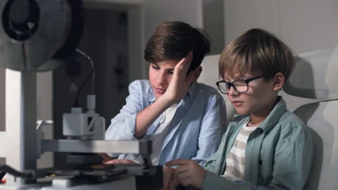 Schoolchildren observe a 3D printer in operation on a table Stock Footage 335374180
