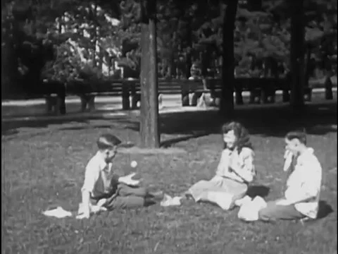 Schoolchildren in a park invite a new friend to picnic with them, outdoors, in Stock Footage