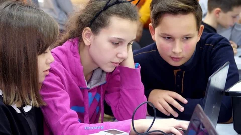 Schoolchildren working together on a laptop in computer class, typing on a Stock Footage 118847064