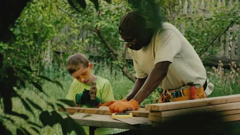 Schooler hammers nail into plank under control of specialist Stock Footage 200676333