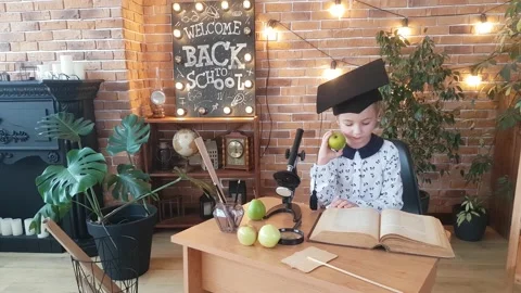 A schoolgirl in an academic square cap  studies an encyclopedia Stock Footage 169048043