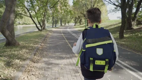 Schoolgirl boy with a backpack run through the park home from school dream on a Stockbeeldmateriaal 140082782