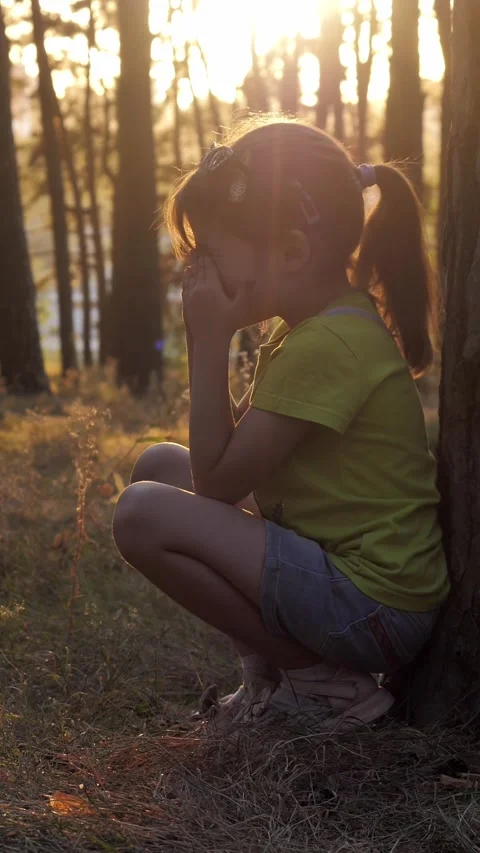 Schoolgirl cries while sitting alone on the grass in the forest  Video stock 341658884