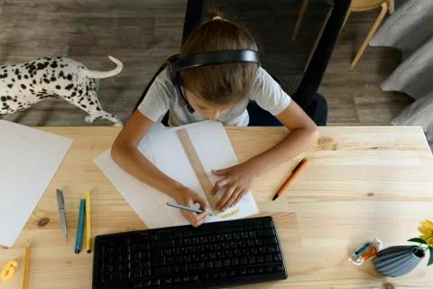 Schoolgirl does lessons in front of the computer, view from above. Stock Photos