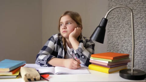 Schoolgirl dreaming while doing homework. Girl sitting at a desk, propping her Video stock 128378097