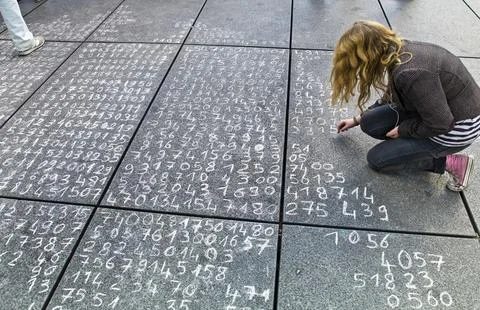 A schoolgirl has written a maths problem on a pavement. Austria Stock Photos
