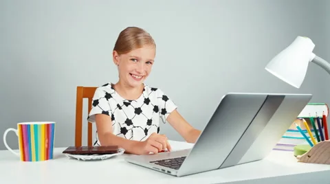 Schoolgirl holds chocolate and gives you it at camera sitting at the desk Stock Footage