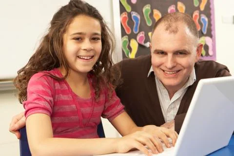 Schoolgirl In IT Class Using Computer With Teacher Stock Photos
