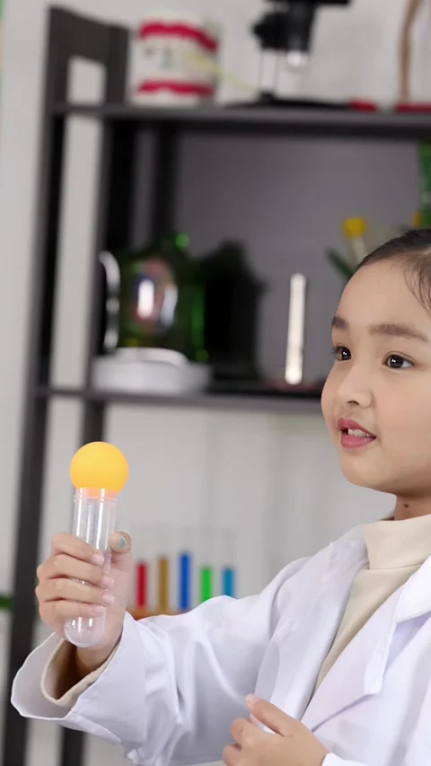 Schoolgirl in Lab Coat Performing Science Experiment with Ping Pong Ball Stock Footage 338312996