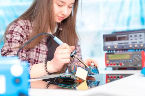Schoolgirl in laboratory robots debug microcontroller Stock Photos