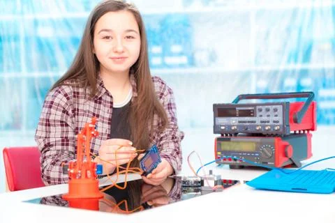 Schoolgirl in laboratory robots debug microcontroller Stock Photos