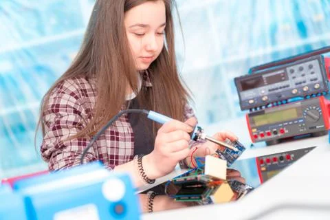 Schoolgirl in laboratory robots debug microcontroller Stock Photos