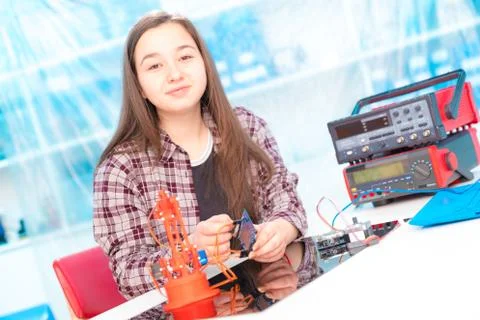 Schoolgirl in laboratory robots debug microcontroller Foto stock