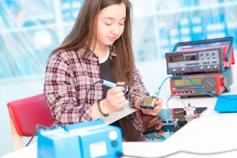 Schoolgirl in laboratory robots debug microcontroller Stock Photos