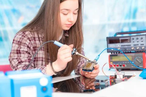 Schoolgirl in laboratory robots debug microcontroller Foto stock