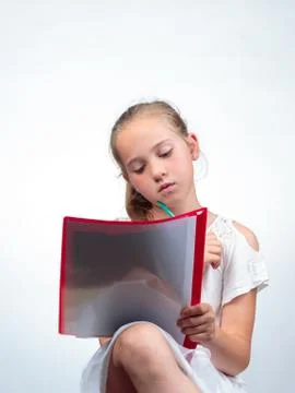 Schoolgirl looking at a note pad while holding a pencil Stock Photos