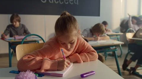 Schoolgirl making notes in notebook. Smart student writing in exercise book Stock Photos