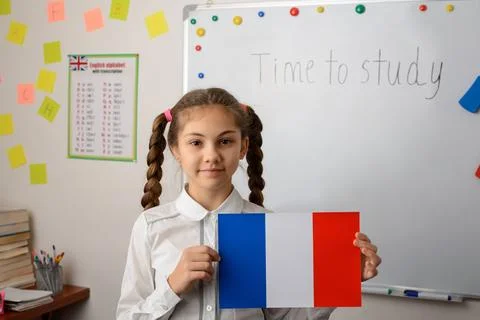 Schoolgirl in school classroom with french flag near the whiteboard Stock Photos