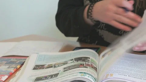 The schoolgirl sitting at a desk reads a tutorial Stock Footage 72532194