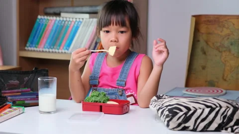 Schoolgirl sitting at a table and eating healthy food during break at school. 스톡 동영상 201181753