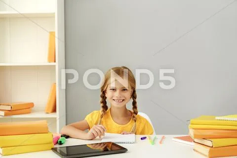 Schoolgirl sitting at the table Stock Photos