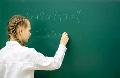 A schoolgirl solves examples on a chalkboard. The idea of creative education Stockfoto's