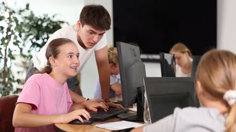 Schoolgirl using computer and teacher helping to him in classroom 스톡 동영상 276342697