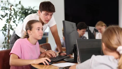 Schoolgirl using computer and teacher helping to him in classroom 스톡 동영상 306981527