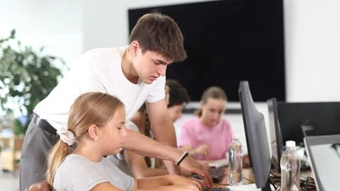 Schoolgirl using computer and teacher helping to him in classroom 스톡 동영상 319487559