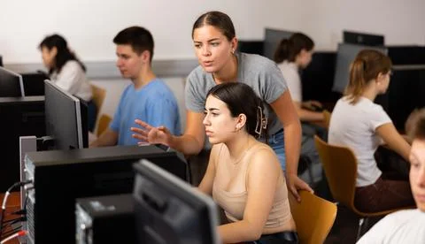 Schoolgirl using computer and teacher helping to him in class room Foto stock