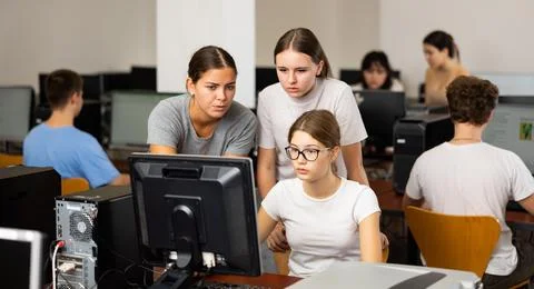 Schoolgirl using computer and teacher helping to him in class room Stock Photos