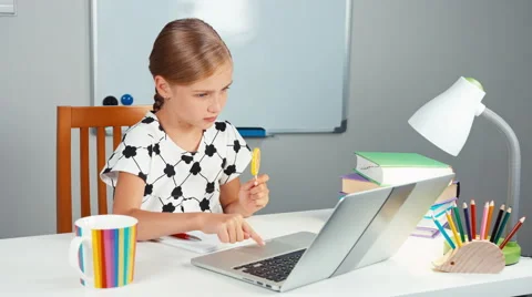 Schoolgirl using her laptop and laughing. Kid licking lollipop and smiling Stock Footage
