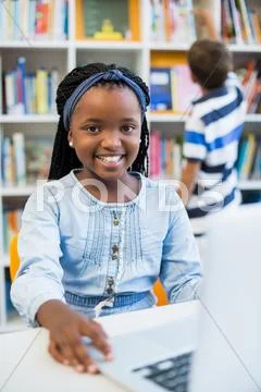 Schoolgirl Using Laptop In Library