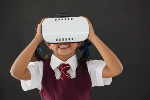 Schoolgirl using virtual reality headset against blackboard 写真素材
